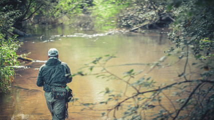 A fisherman catches spinning in the waders. Trout fishing.
