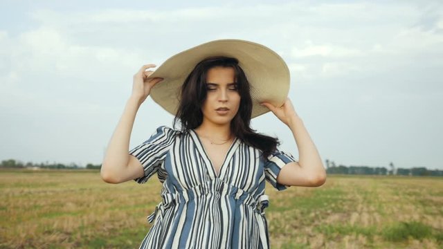 Woman In Hat Walking On Field. Woman In Hat.Wicker Hat. Romantic Woman Walking On Field. Girl Relaxing. Girl Walks Through Field. Pretty Ledy In Dress.