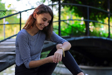 Young and beautiful girl dressed in gray putting on a gold and quartz watch.  Girl with gold...