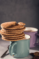 Old mug with chocolate milk and traditional dutch cookies stroopwafels on gray background with copy space. Retro style toned.