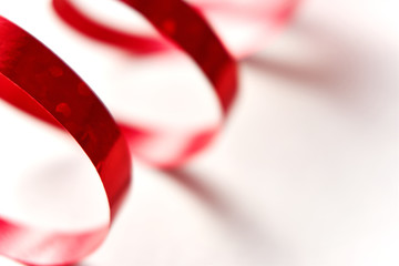 Red curly ribbon on white background. Abstract image of serpentine with curls for use as a christmas, anniversary, valentine or celebration background with copy space.  