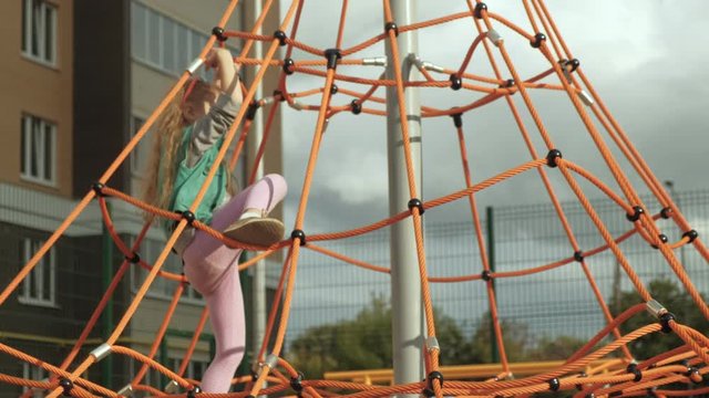 A child climbs a rope horizontal bar in an outdoor playground