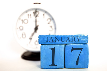 january 17th. Day 17 of month, handmade wood calendar and alarm clock on blue color. winter month,...