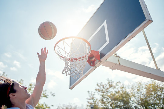 Photo of athlete throwing ball into basketball hoop against blue sky