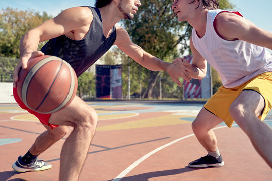 Image of sporty men playing basketball on playground on summer day.