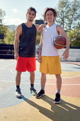 Full-length image of two athletes with basketball on playground .