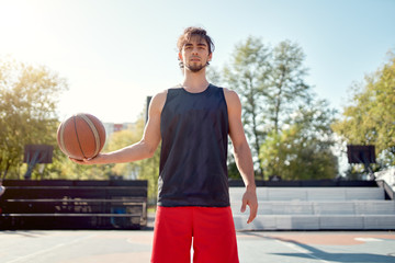 Portrait of athlete man in blue T-shirt with ball in his hands on sports field .