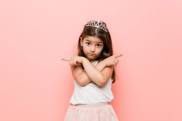 Little girl wearing a princess look points sideways, is trying to choose between two options.