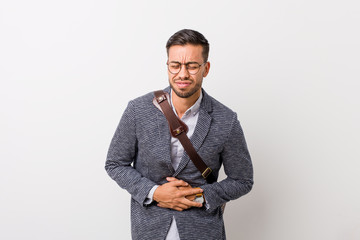 Young business filipino man against a white wall sick, suffering from stomachache, painful disease...