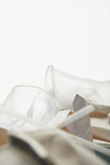 close up view of transparent plastic cups in pile of rubbish on white background