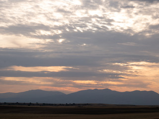 Amanecer con nubes y montañas en campo de cultivo