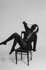 Beautiful model sitting on chair in studio, bw