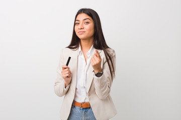 Young arab woman holding a credit card pointing with finger at you as if inviting come closer.