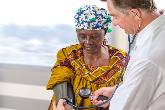 doctor in wite coat measuring blood pressure of anfivan olf woman in hospital