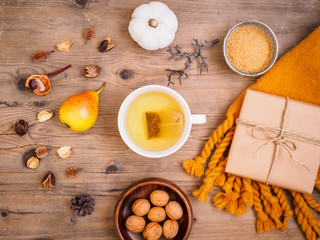 Eine Tasse Tee, Geschenkpaket, Birne und Walnüsse auf einem Holztisch, Herbst, Flat lay