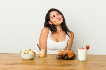 Young curvy woman taking a breakfast dreaming of achieving goals and purposes