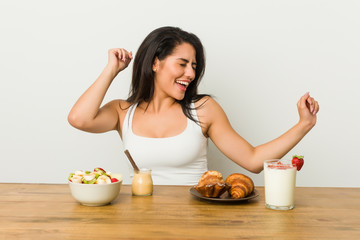 Obraz na płótnie Canvas Young curvy woman taking a breakfast dancing and having fun.