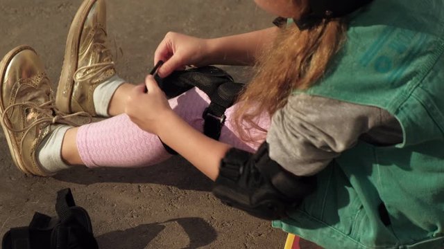 Little girl dresses protection: helmet, knee pads and elbow pads. Sunset