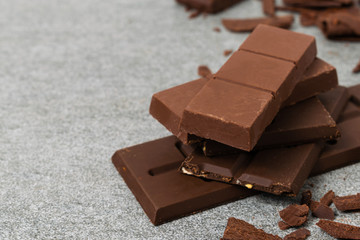Broken chocolate with small piece on tile table.