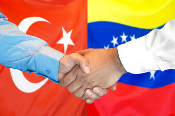 Handshake on Turkey and Venezuela flag background.