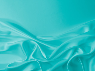 Smooth elegant wavy turquoise silk or satin luxury cloth fabric texture, abstract background design.