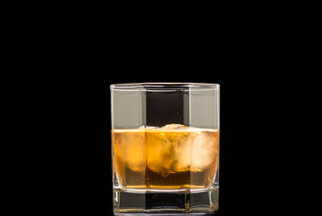 glass of whiskey with ice and a splash and spray from falling on a black background