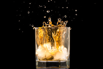 glass of whiskey with ice and a splash and spray from falling on a black background