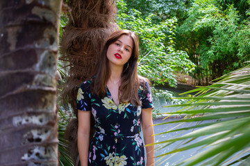 Young woman with stylish clothes posing in a paradisiacal park at sunset	