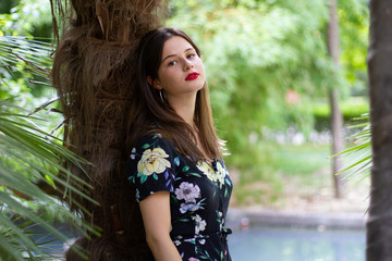 Young woman with stylish clothes posing in a paradisiacal park at sunset	