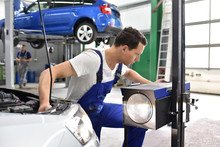 adjusting the headlights on the car by mechanics in a garage