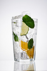 Glass of lemonade with lemon, lime and mint on white background.  Soda water with citrus and ice. Lime and orange in sparkling water