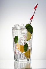 Glass of lemonade with lemon, lime and mint on white background.  Soda water with citrus and ice. Lime and orange in sparkling water