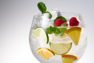 Glass of lemonade with lemon, lime and mint on white background.  Soda water with citrus and ice. Lime and orange in sparkling water