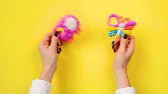Mother shakes baby rattle on a yellow background 