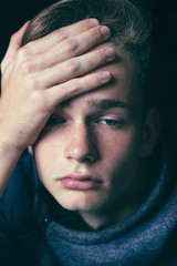 Fototapeta premium Portrait of an anxious thoughtful teenager in hoodie against a brick wall. Concept of problems of adolescents, problems of adolescents and parents