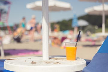 Juice on the table at the beach. Blurred people background. Copy space concept.