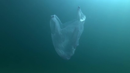 Plastic pollution, Blue plastic bag swims underwater in sunray. Plastic debris underwater. Plastic garbage environmental pollution problem 