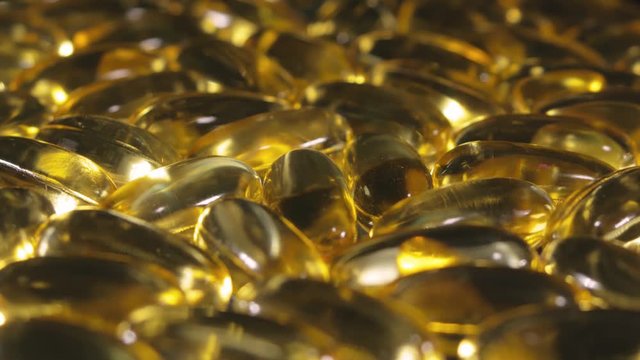 Omega 3 gold fish oil capsules, rotation background, macro. Capsule gold oil gel supplement rotating movement, Omega 3 Fish Oil, Healthcare pharmacy medical concept.