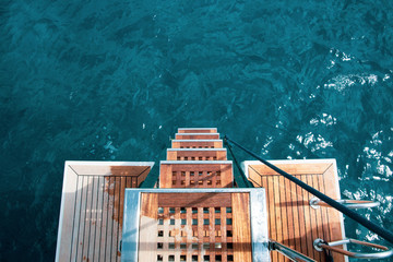 Yacht Life: the rear deck of a luxury yacht, view from above, on a turquoise, mediterranean sea. Private cruise.