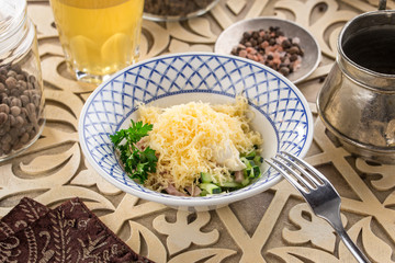 Fresh salad with cucumber, cheese and ham and glass of lemonade on oriental wooden table