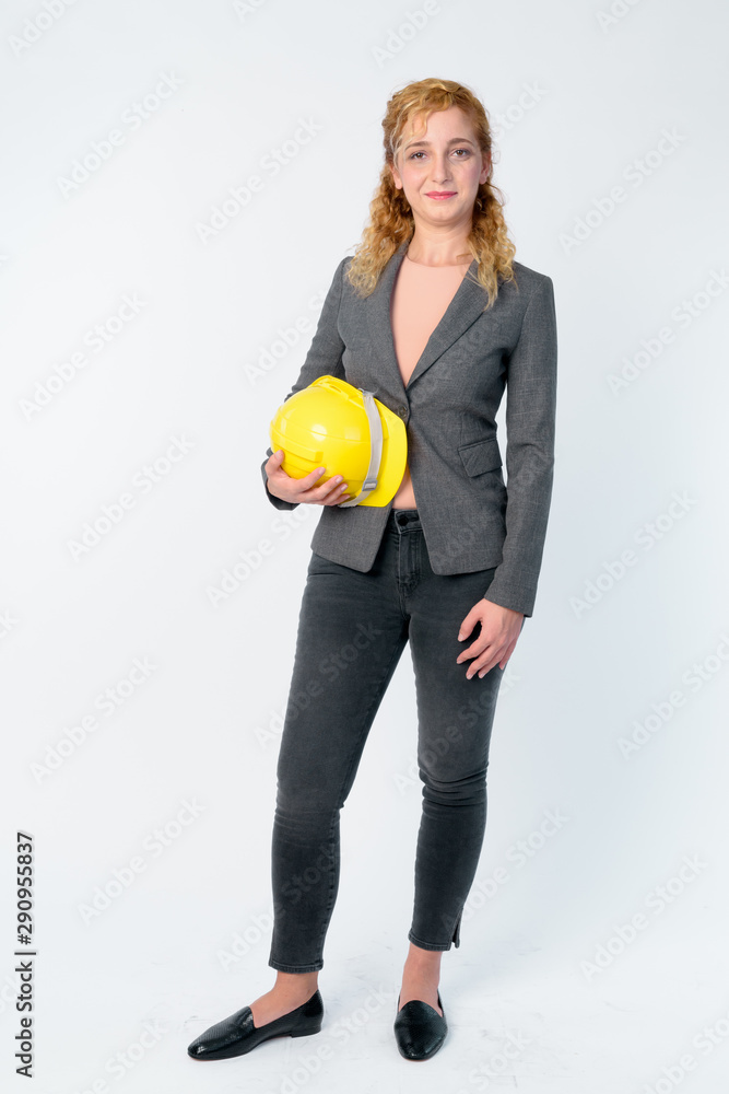 Wall mural Full body shot of blonde businesswoman as engineer holding hardhat