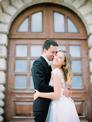 Fototapeta premium Stylish and beautiful bride and groom near the old Church. Film analog photography