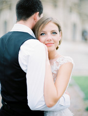 Fototapeta premium Stylish and beautiful bride and groom near the old Church. Film analog photography
