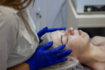 Fototapeta premium Beauty Clinic.woman gets a professional facial procedure. Beautician makes massage on a woman's face. face renewal