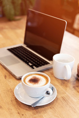 cup of coffee and laptop on table