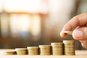 Saving money. businessman hand putting stack coins to show concept of growing savings money finance business and wealthy.  soft focus. Leave space to write a description of the message.