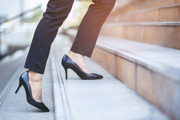 modern businesswoman working woman close up legs walking up the stairs in modern city in rush hour...