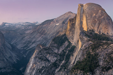 Wide angle view of the Half Dome and its surroundings at dusk under a purple sky