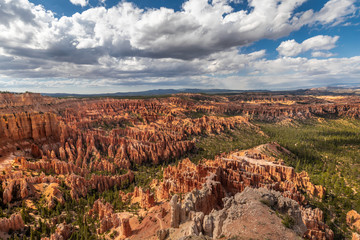 Wide angle view of the Bryce Canyon under a blue sky with puffy clouds