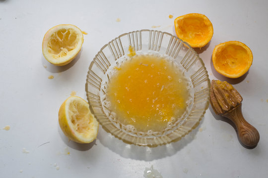 Freshly Squeezed Lemon Juice with Pulp, Reamer, and Lemon Halves on a White Background